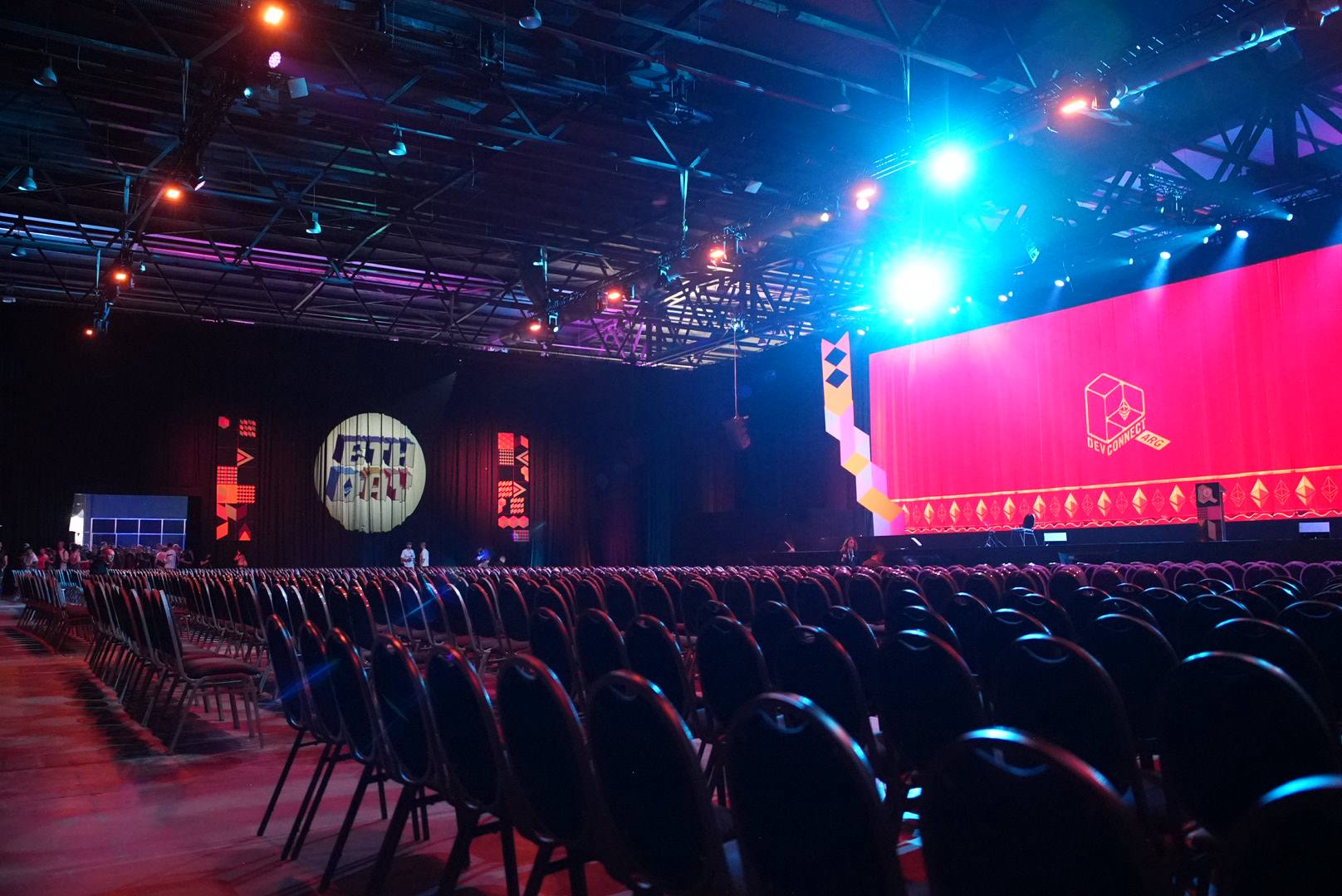 Empty Devconnect Buenos Aires main hall with rows of chairs facing the lit stage and Devconnect signage